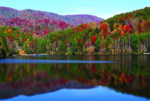 A lake reflects the fall colors of the surrounding mountains on State Route 60.