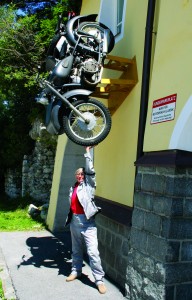 Sue is not really holding up that motorcycle; it merely serves as an advertisement for a motorcycle shop, museum and hostel in Austria.