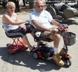 Takes Two to Tangle: Yes, that is a skateboard double as tandem sidecar. Tom Hal, a retired pharmacist, and his wife have been riding together for 50 years! He carries the little electric scooter and special passenger “chair” on the back of his full-sized side car.