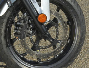 Large scalloped brake rotor is squeezed by 3-piston caliper; ABS is optional.