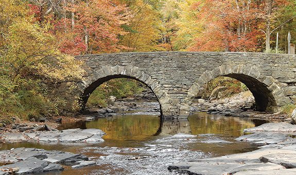 The Tusten Stone Arch Bridge stands in all nature’s golden glory, at Ten Mile River in Tusten, New York, off State Route 97.