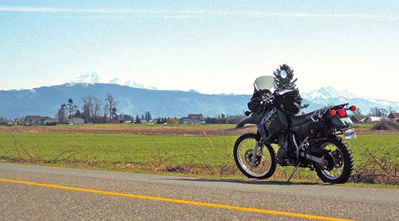 My KLR is just feet away from the border. Mount Baker stands gleaming in the sun to the left.
