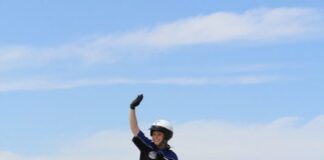 Smiling Megan performs atop a crowd-pleasing stunt, waving to the enthusiastic crowd