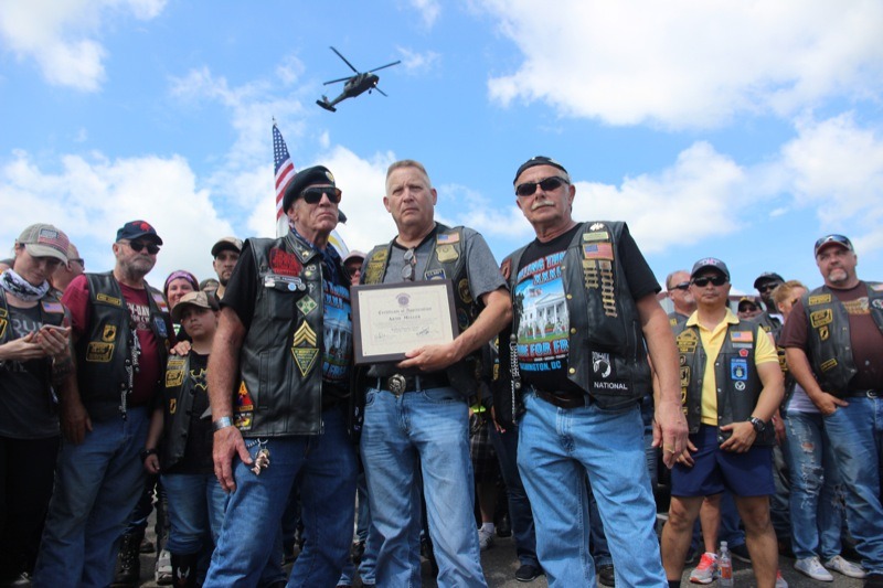 Andrew “Devildoc” Mutchler, president of Hogs and Heroes, presents a plaque to Artie Muller, Director of Rolling Thunder