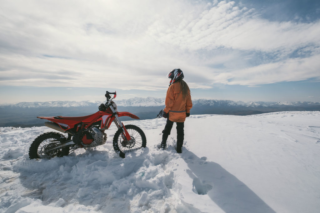 Women in snow next to motorcycle, Yuasa Battery