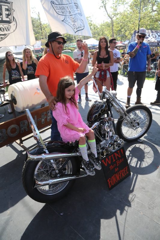 Paul Kuvelis, the winner of the a Prism-built Shovelhead Chopper, poses for some pictures with his new best friend, a little girl who was chosen from the crowd to draw the winning ticket